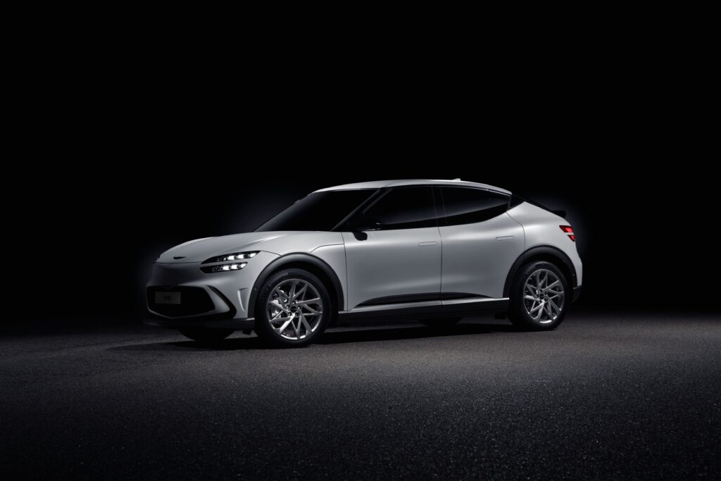 Sleek Genesis GV60 electric SUV in a studio with a black background, showcasing its elegant design.