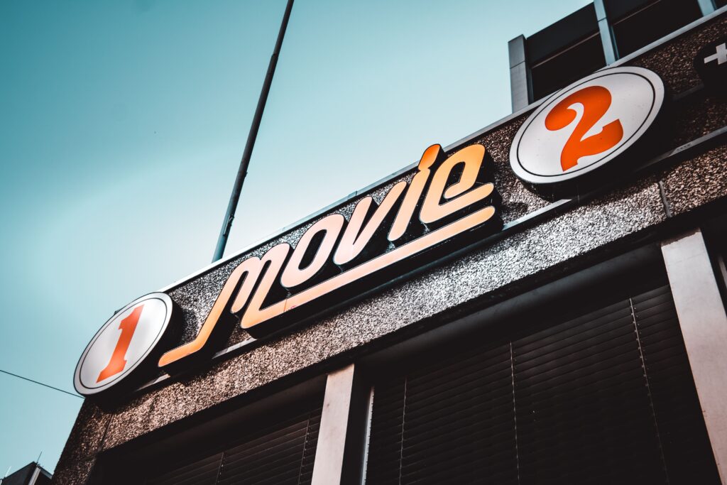 Low-angle shot of a vintage movie theater sign in Bern, Switzerland with a clear blue sky.