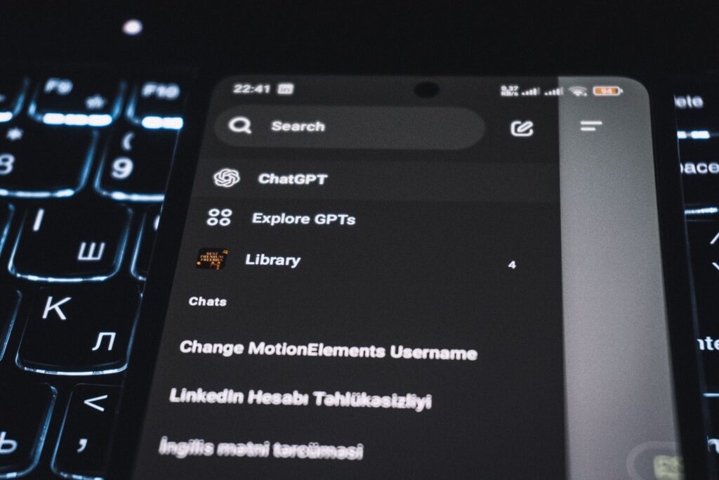 Close-up of a smartphone displaying a chat app interface with a backlit keyboard in the background.