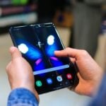 Close-up of hands holding a foldable smartphone showing a butterfly on the screen.
