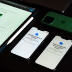 High-angle view of digital devices including iPhones and an iPad on a desk, showcasing data transfer.