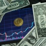 Bitcoin coin on a tablet showing stock chart, surrounded by dollar bills.