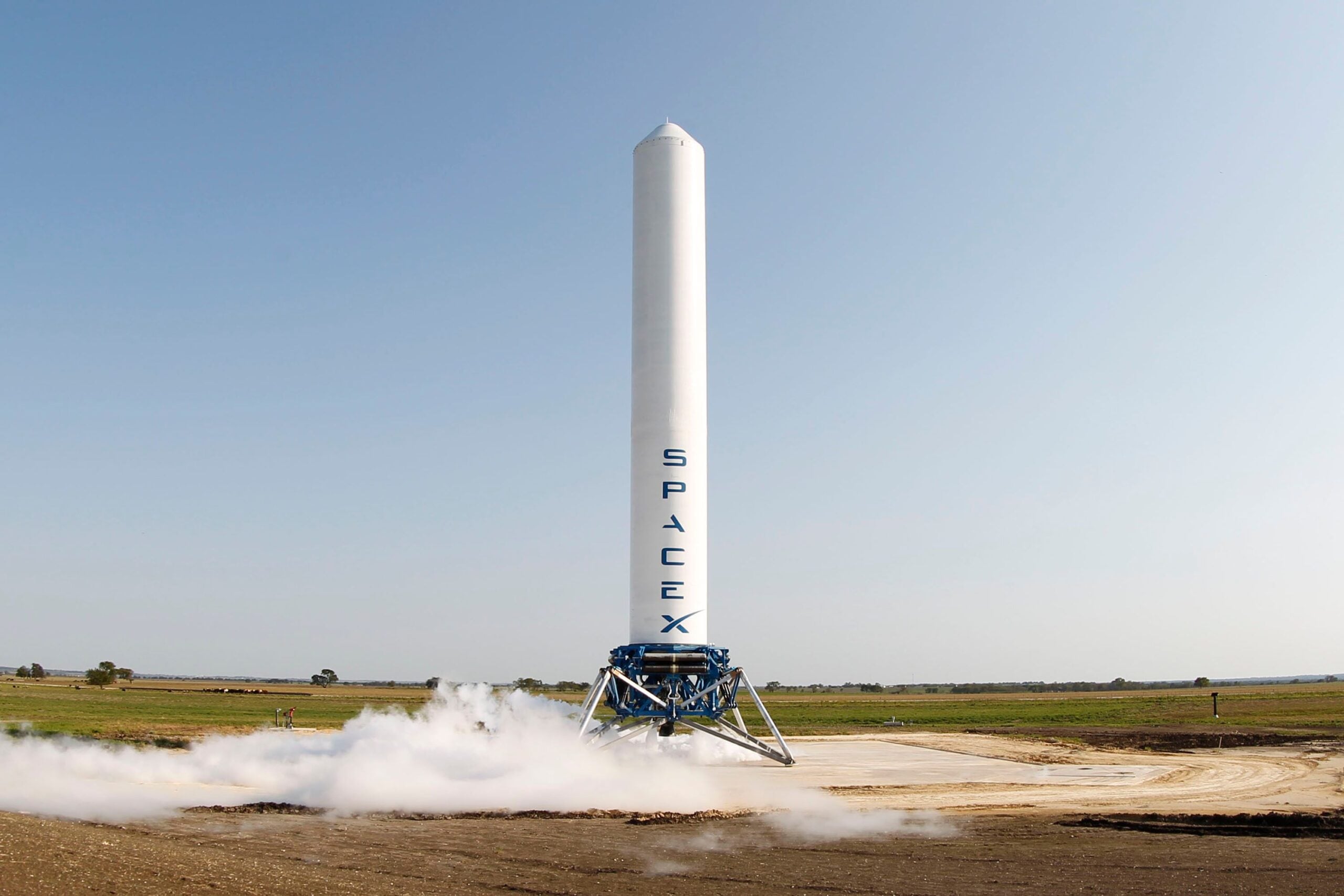 A SpaceX rocket prepares for launch in a rural landscape, capturing a sense of technological advancement.