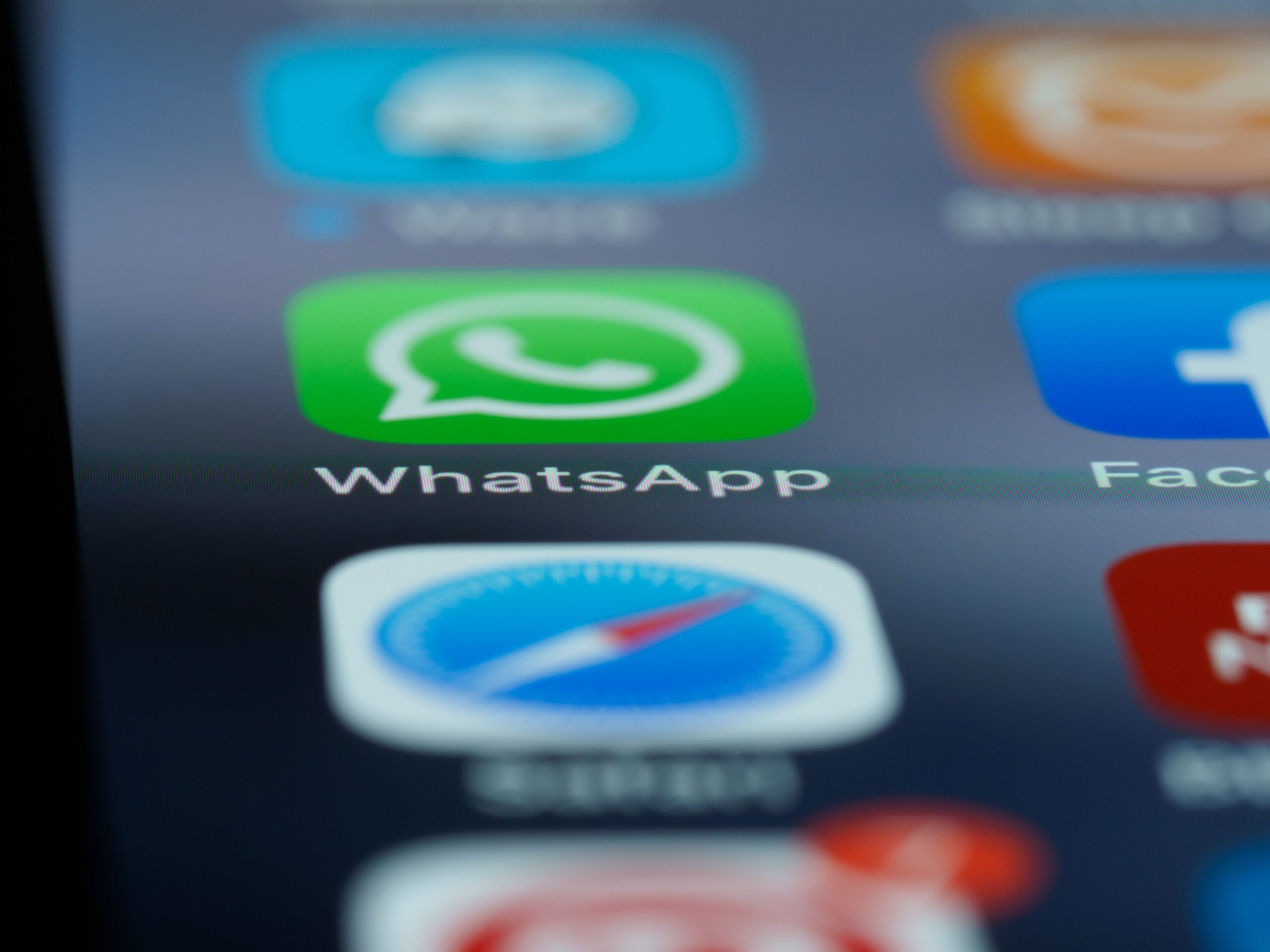 Detailed close-up of a smartphone's home screen displaying popular applications like WhatsApp.